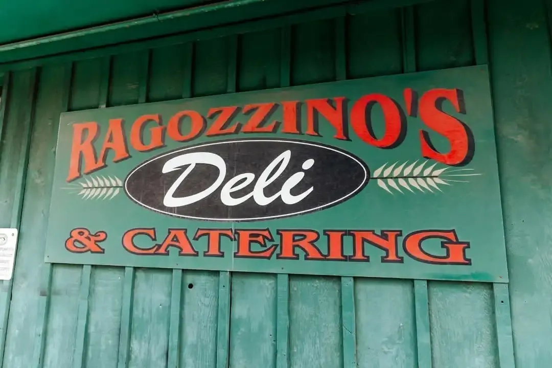 The painted Ragozzino's Deli & Catering sign on the green board wall